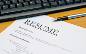 Picture of a printed resume on a desk, next to a keyboard and a pen.
